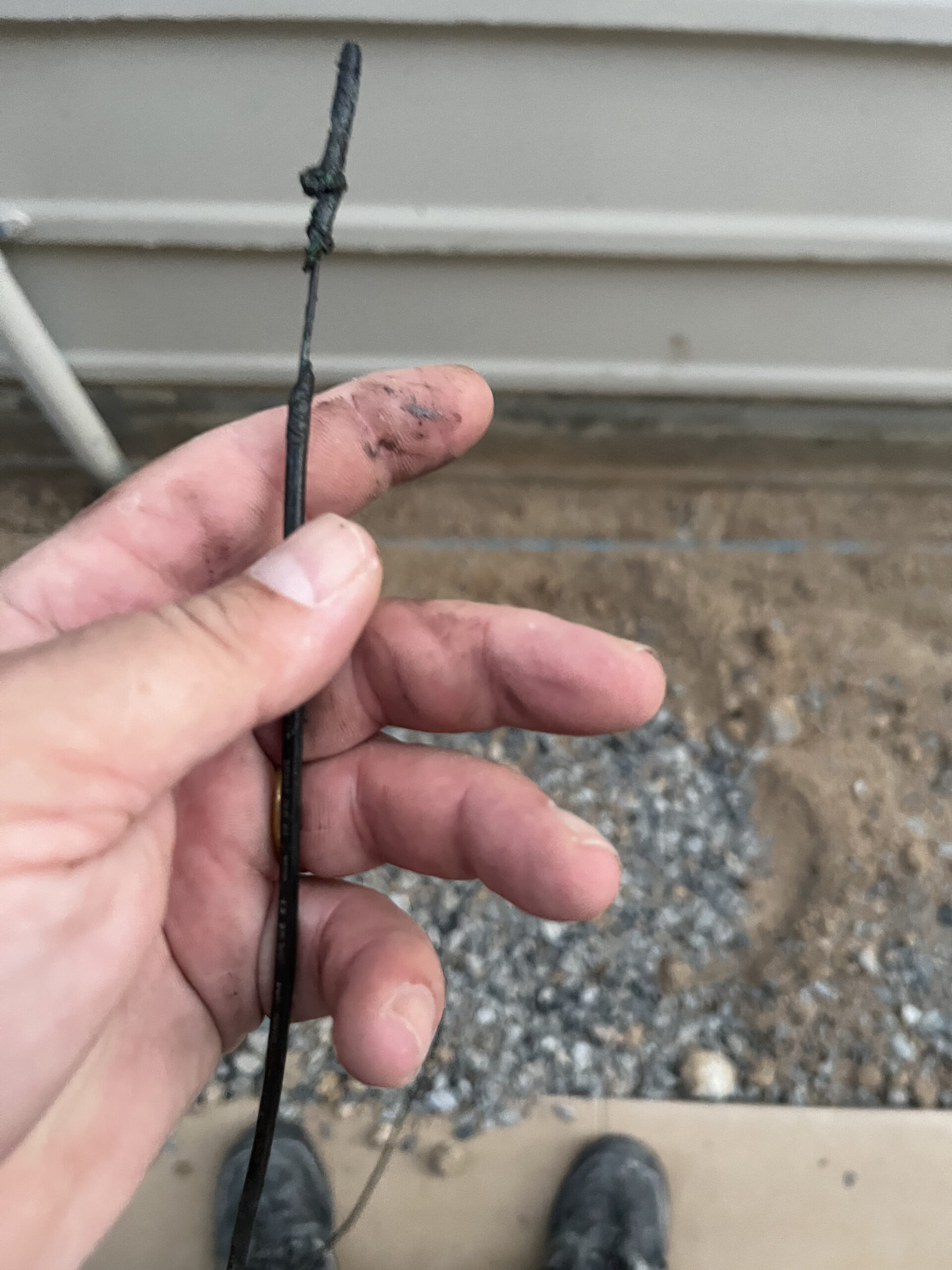 Severely melted and charred electrical wire with insulation completely burned off due to overloading.