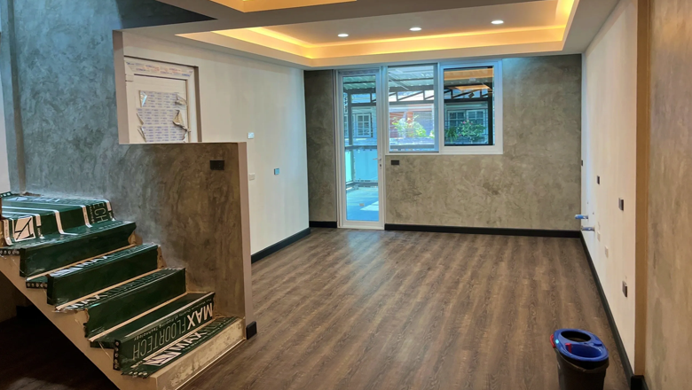ACES Pattaya turnkey interior refurbishment showing finished wood flooring, textured rendered walls, and warm cove ceiling lighting