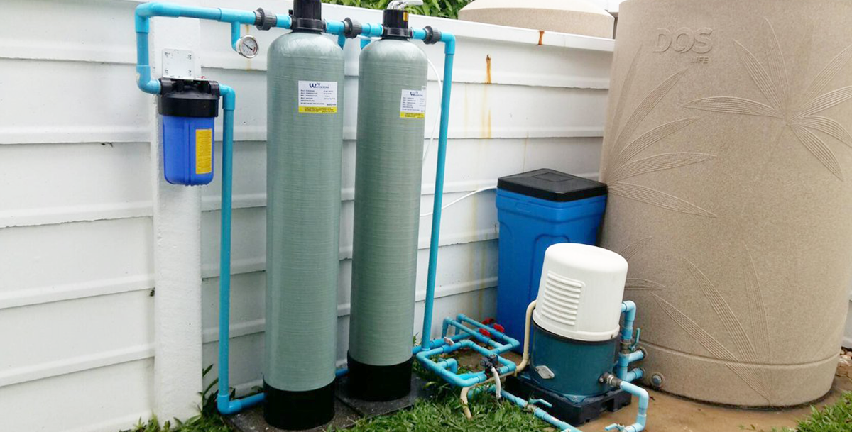 ACES Pattaya outdoor whole-house water filtration system featuring dual FRP media filter tanks, booster pump, and water storage tank