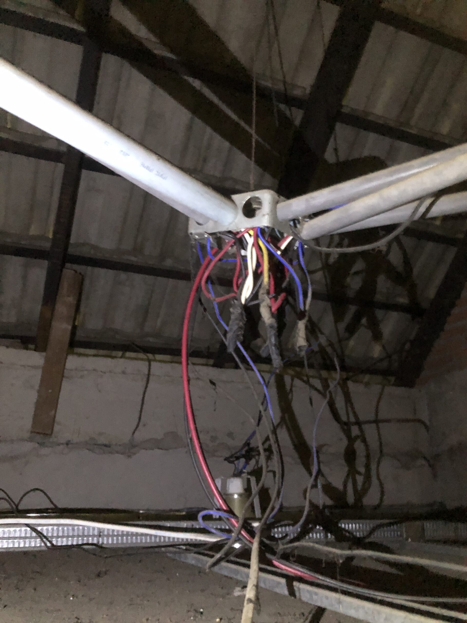 A chaotic mess of exposed, untidy ceiling wires hanging out of an open junction box, uncovered during an electrical safety inspection in Pattaya.
