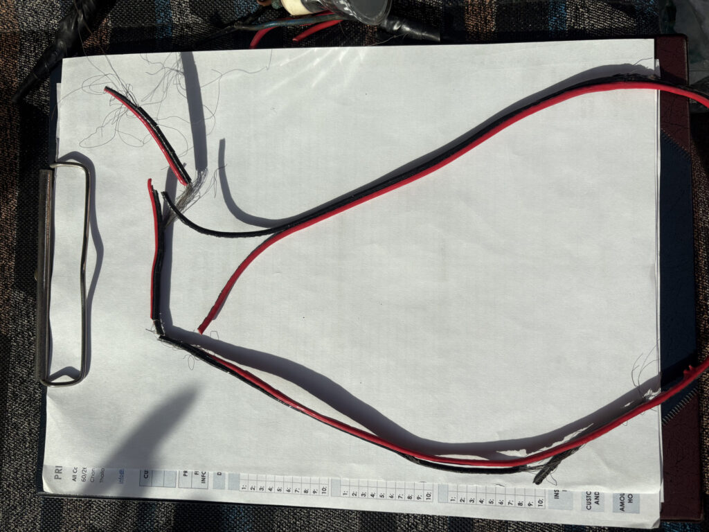 A thin 1 sqmm low-voltage speaker cable incorrectly used by an amateur installer to power a 4 kW shower heater, displayed on an ACES Pattaya inspection clipboard.