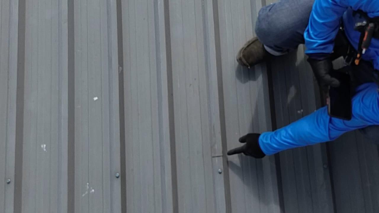 Technician inspecting a corrugated metal roof prior to solar panel installation.