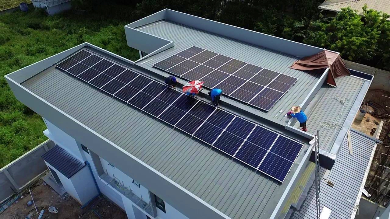 Technicians installing solar panel arrays on a modern residential metal roof.