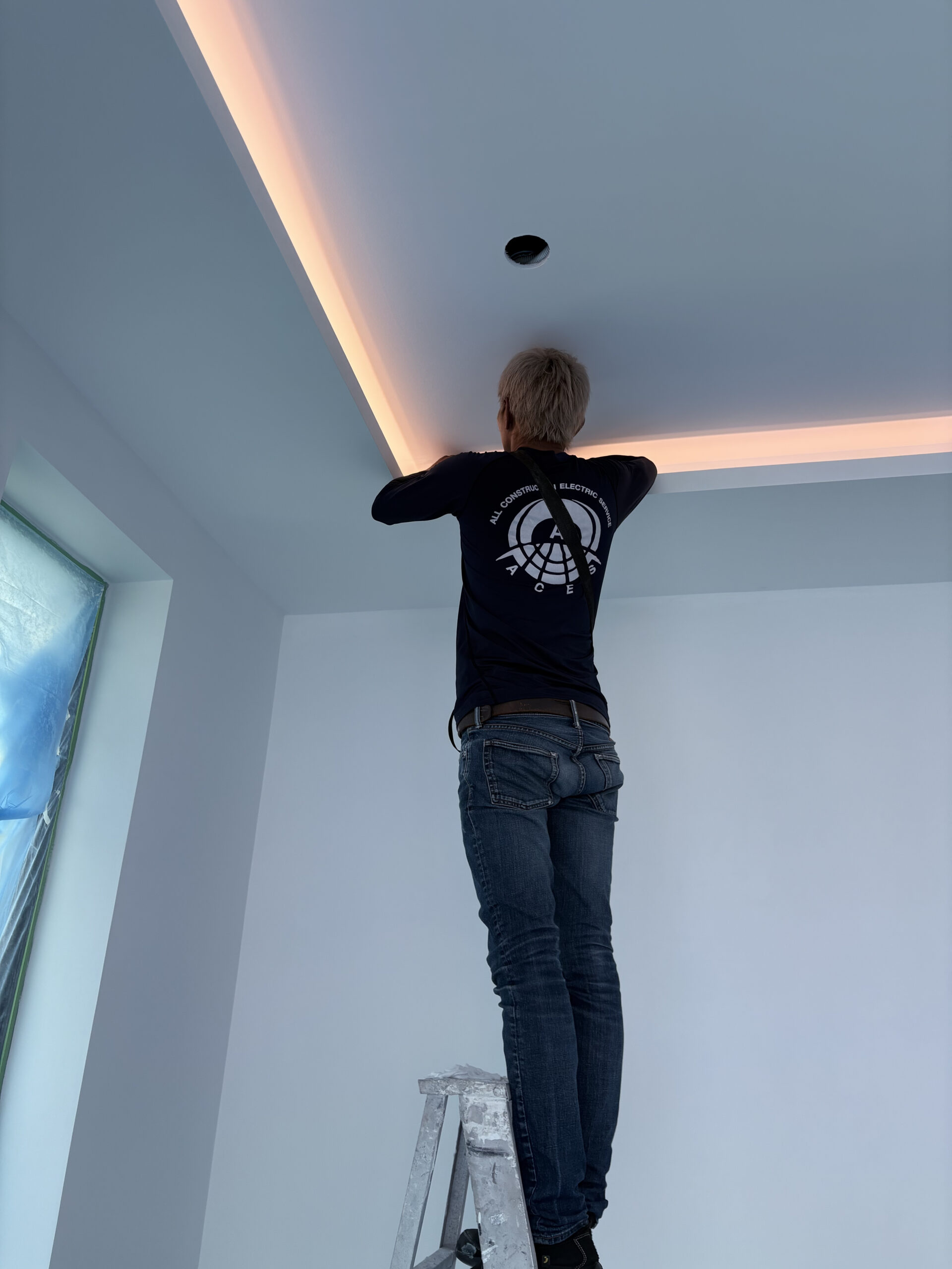 Technician installing warm LED cove lighting in a drop ceiling during professional property maintenance and electrical work in Pattaya