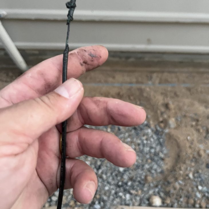 Severely melted and charred electrical wire with insulation completely burned off due to overloading.